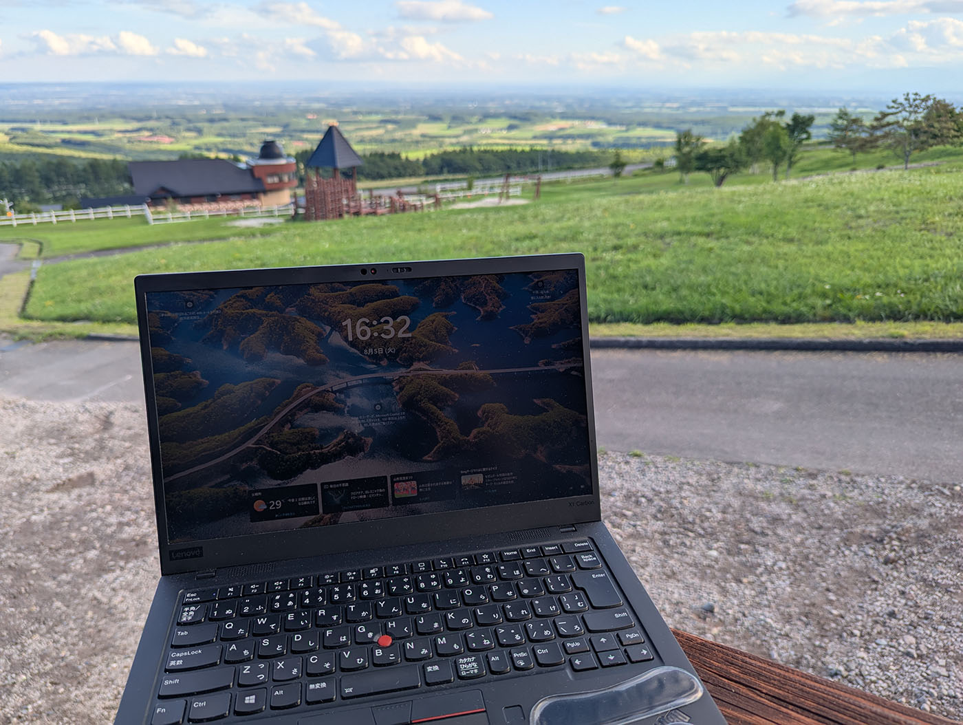 十勝平野を望む高台でノートPCを開き、旅先でノマドワークをしている様子