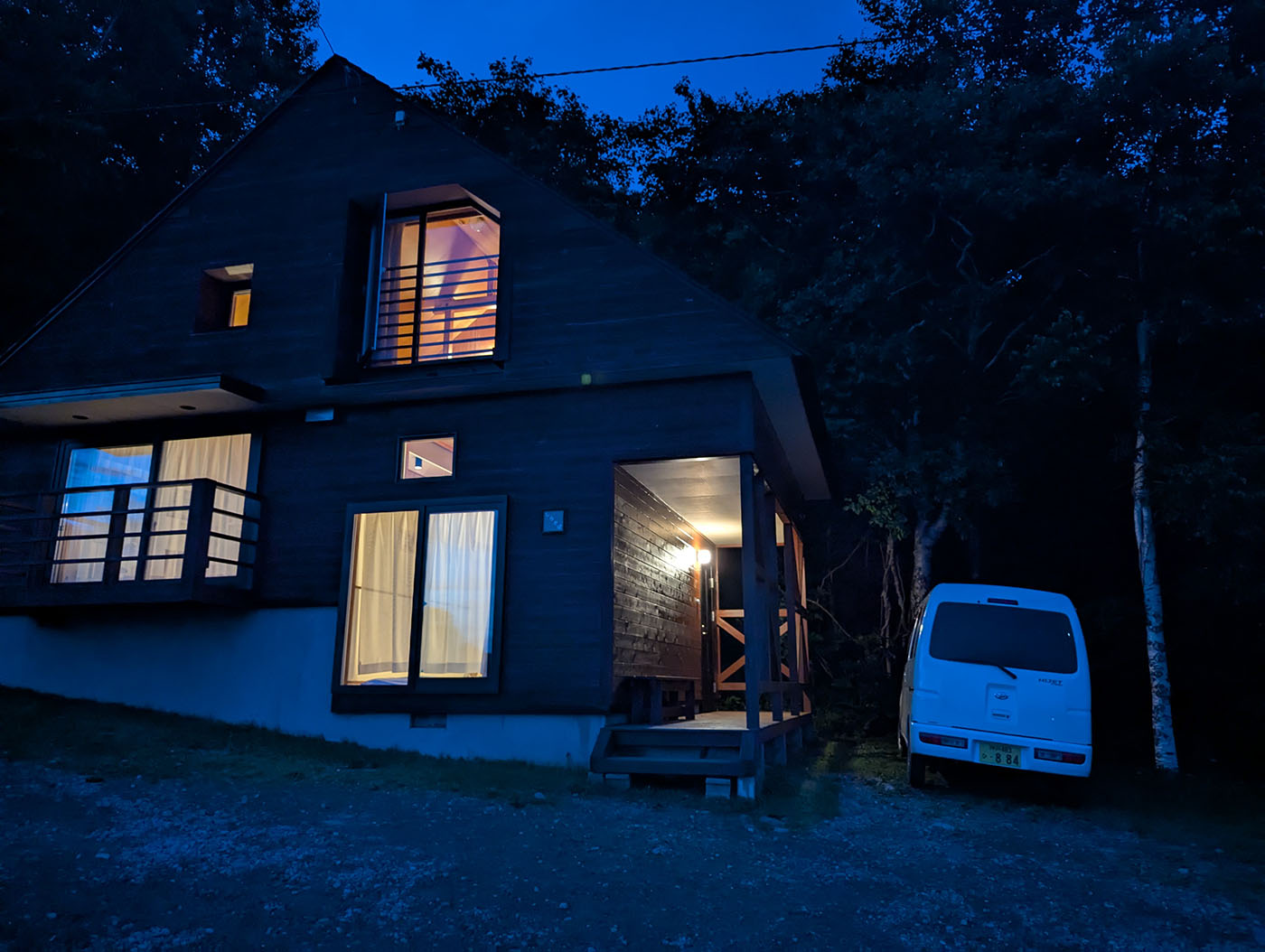 夜のヌプカの里コテージ。室内の明かりが窓から漏れ、隣には白いハイゼットカーゴが静かに停まっている。