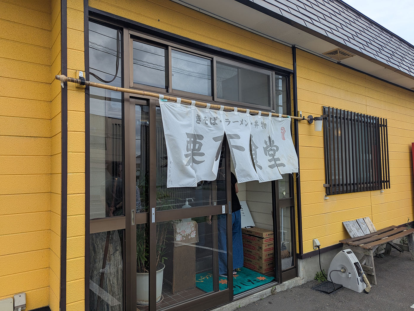 黄色い外壁に白い暖簾がかかる、夕張の「栗下食堂」の入り口。昔ながらの食堂らしい雰囲気が漂う。