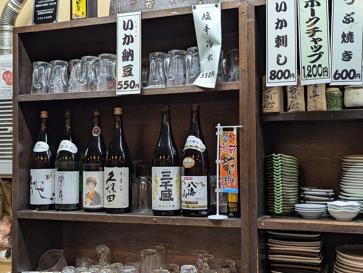 吉田屋の店内に並ぶ地酒と手書きメニュー