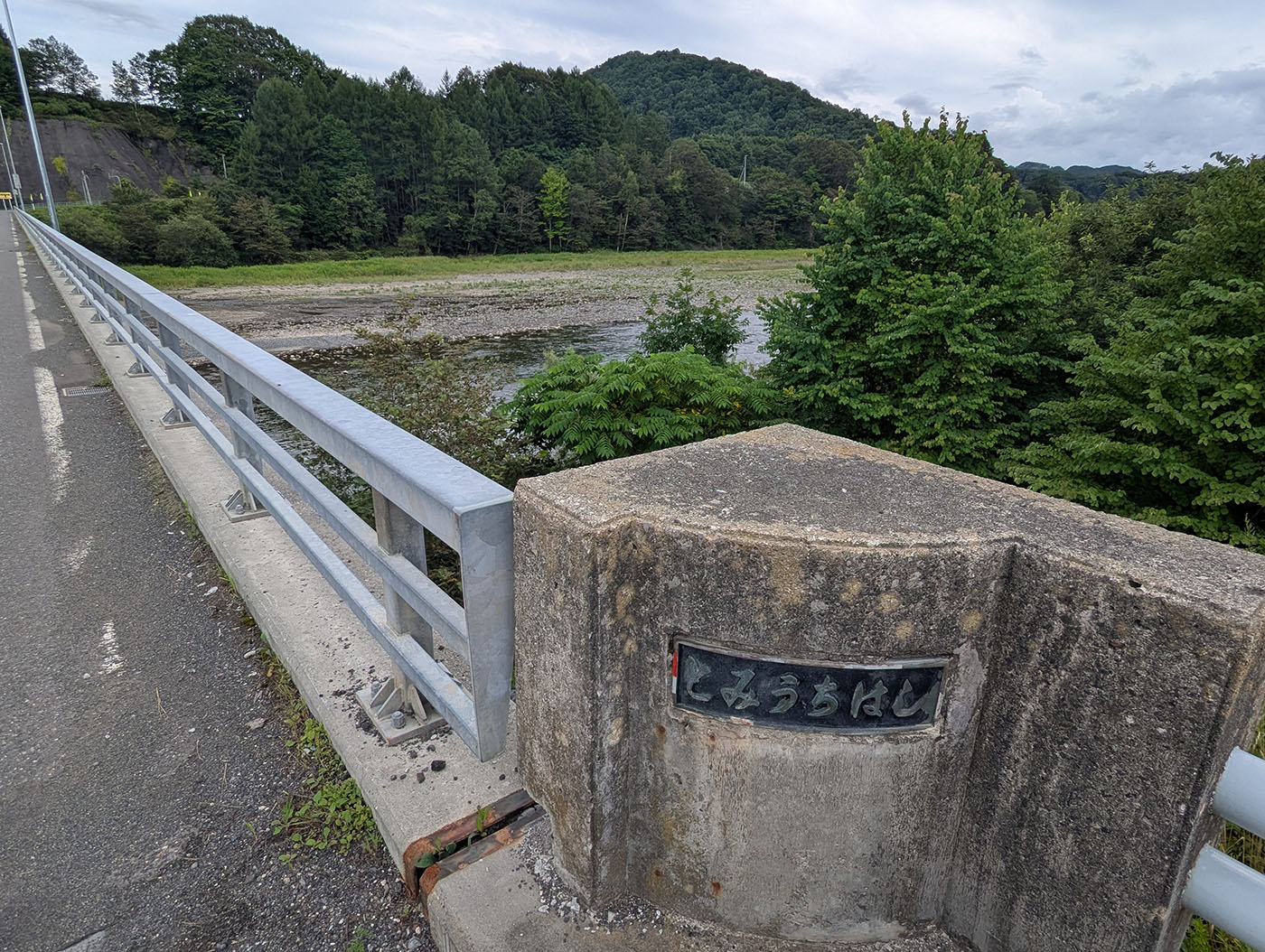 富内橋の橋名板と欄干、背景に鵡川の河川敷と緑豊かな山々が広がる風景