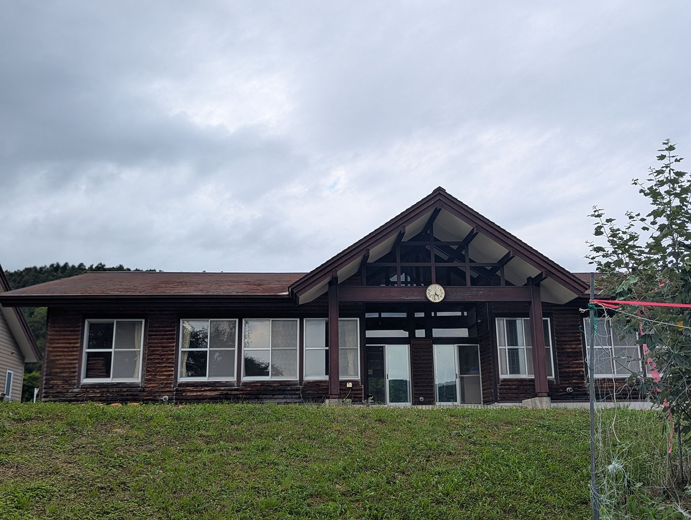 富内銀河ステーション前にある木造平屋建ての高齢者生涯センター。三角屋根の中央には時計が掲げられ、ガラス窓が並ぶ外観が特徴。