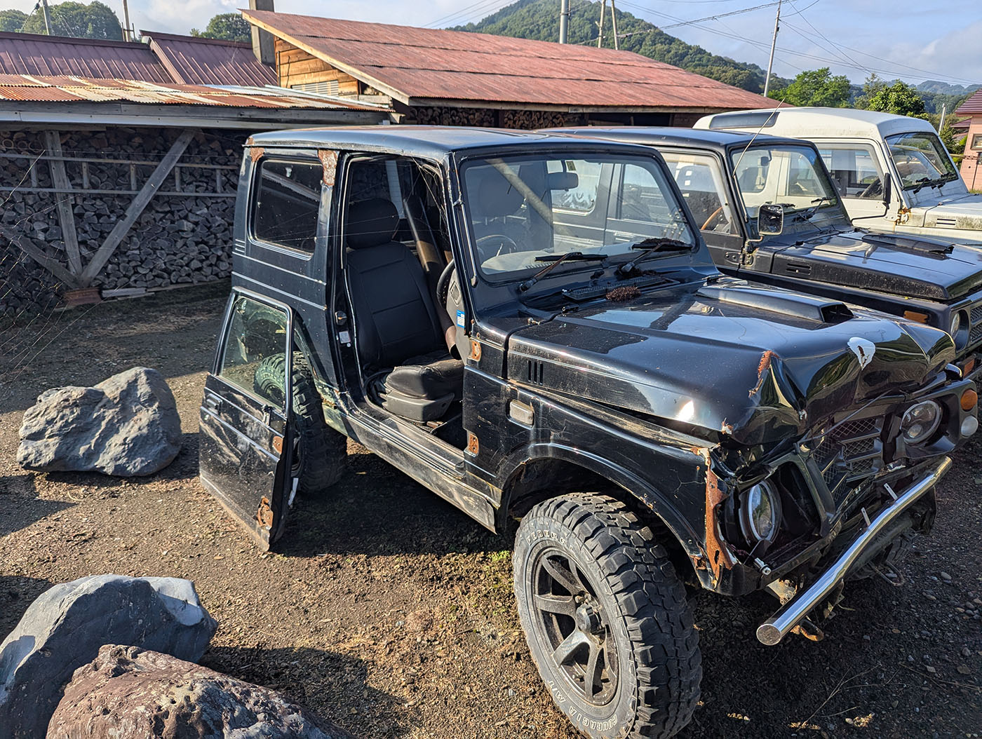 運転席側のドアが外され、車内がむき出しになった黒いジムニー。