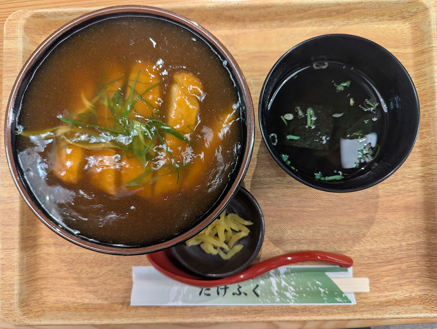 阪神西宮駅エビスタ内「たけふく」のカツカレー丼セット。だしの効いたカレーにとんかつがのり、味噌汁と漬物が添えられている。木のトレーに整った旅の締めの一膳。