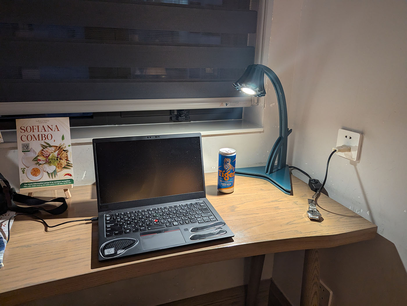 ホテルのデスクでパソコンを設置し、Tigerビールを置いた作業スペース。コンセントには日本のプラグが直接差し込まれている。