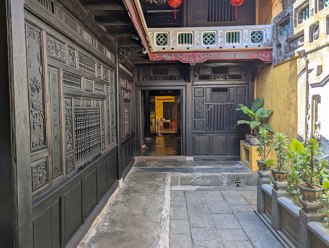 ホイアンのクアン・タン古家。黒塗りの壁に精緻な彫刻が施され、梁と柱が織りなす美しい構造が見える。