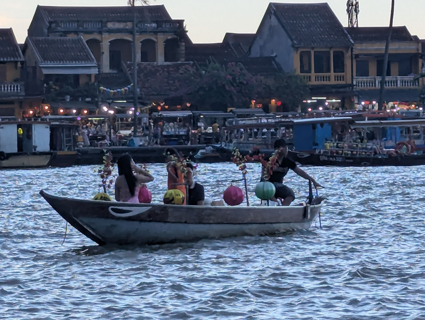 トゥボン川で夕暮れのクルーズを楽しむ人々。小舟にランタンが飾られ、川面が夕陽にきらめいている