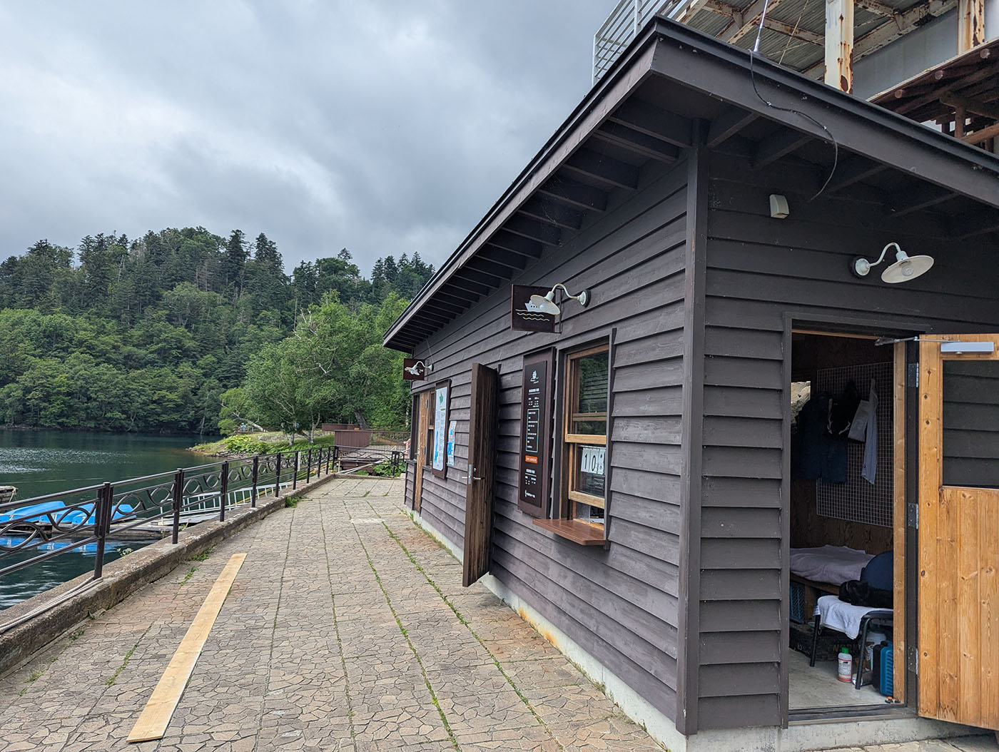 然別湖の湖畔に建つ遊覧船のチケット売り場。奥には静かな湖とボートが見える。