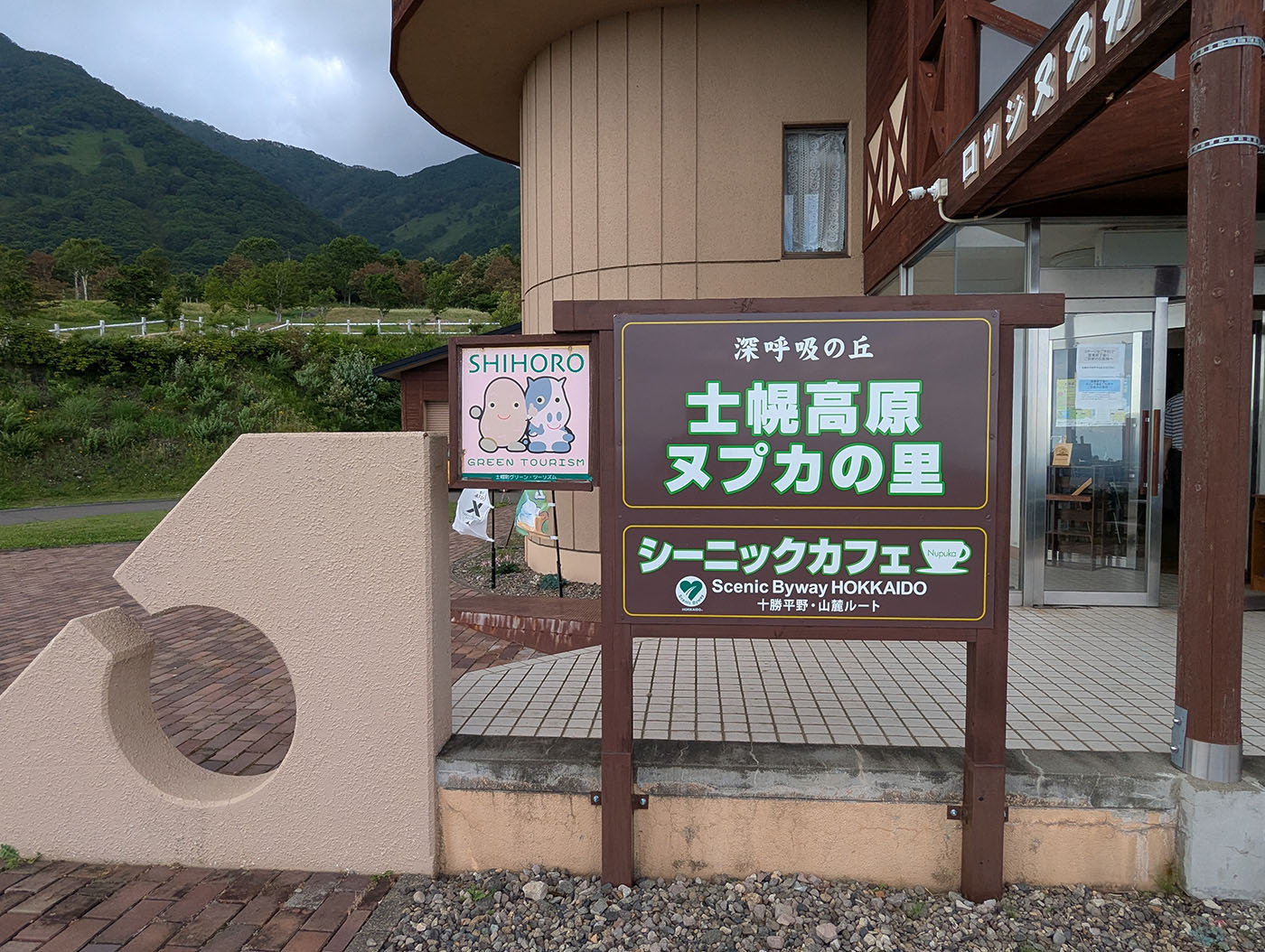 「士幌高原ヌプカの里」の施設看板と入口。マスコットキャラと山の風景が背景に広がる。