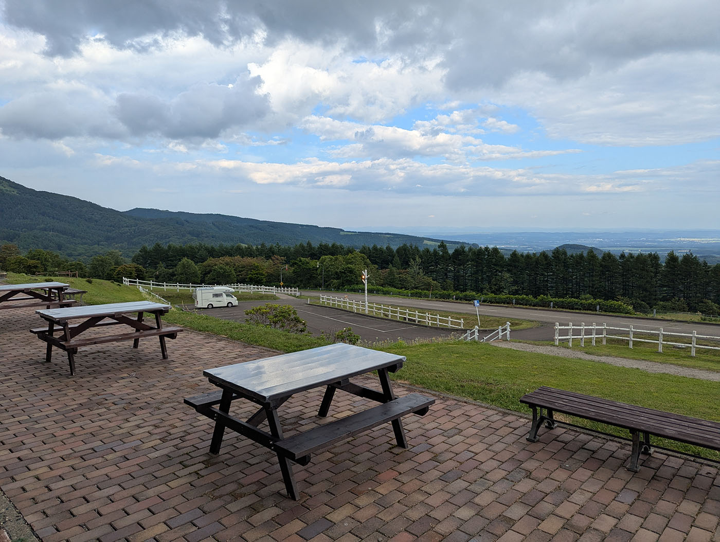 ヌプカの里の展望スペースに並ぶベンチとテーブル。背景には十勝平野と遠くの山並みが広がる。