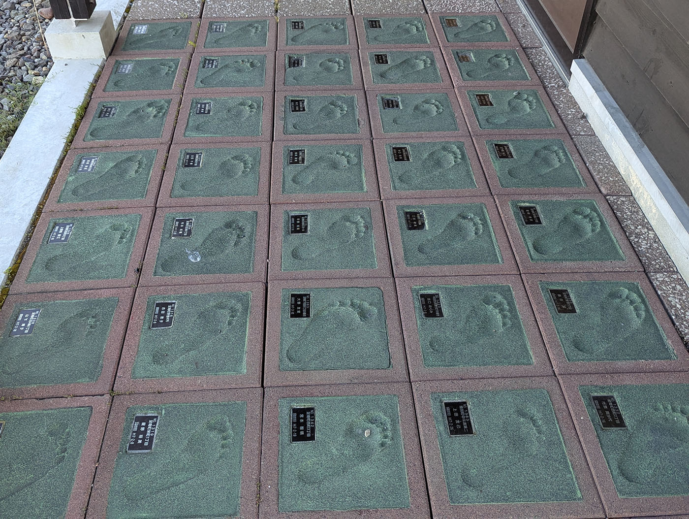 旧足寄駅舎前に並ぶ足形タイル。緑色のタイルに町ゆかりの人々の足跡が刻まれ、黒いプレートに名前が記されている。