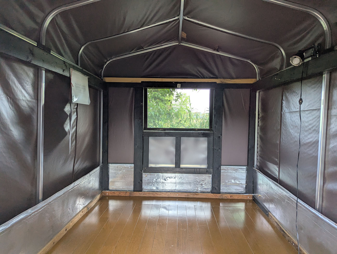 モバイルハウスの内部。両側に壁があり、床は板張り。シンプルながらも居心地の良い空間。