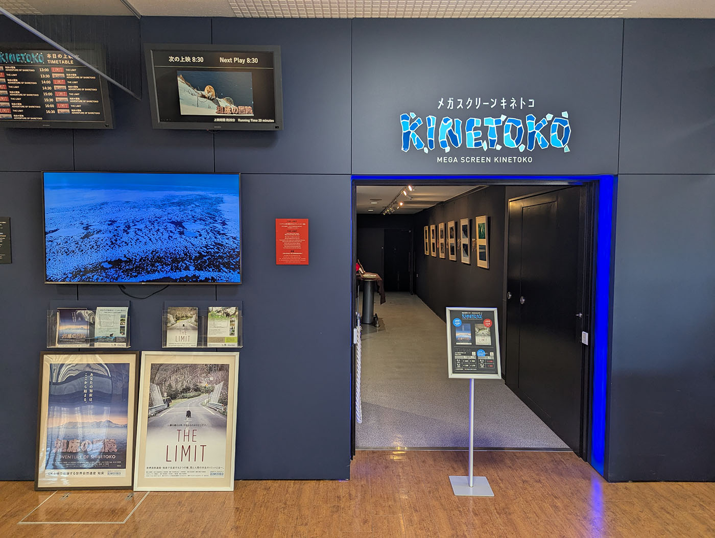知床自然センター内のメガスクリーンキネトコ入口。上映案内やポスターが並び、大型モニターには流氷の映像が映し出されている。