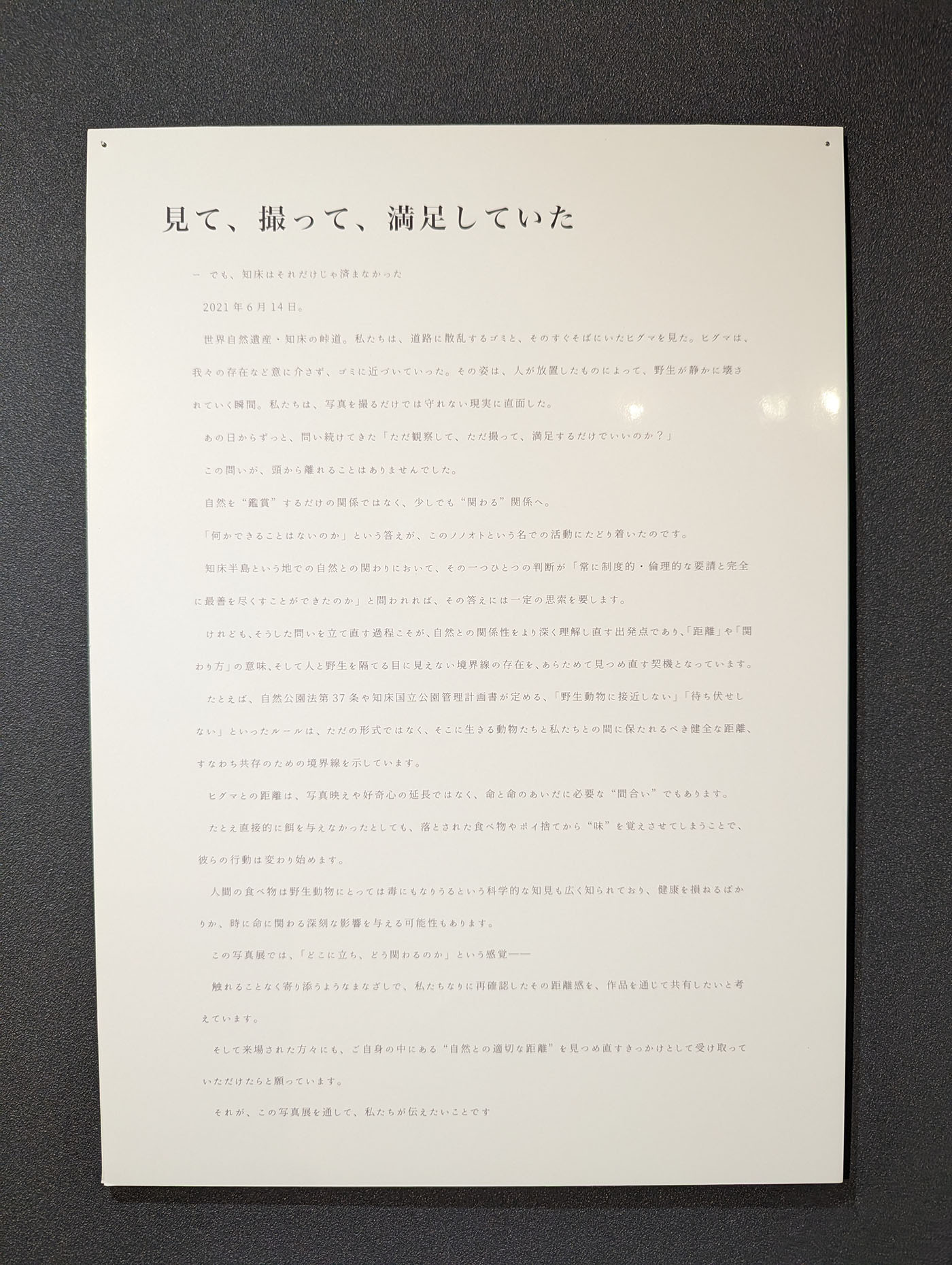 写真展「ノノオト」に展示されたパネル「見て、撮って、満足していた」。知床でのヒグマとの遭遇と、人と野生動物との距離の在り方を問いかける文章が記されている。