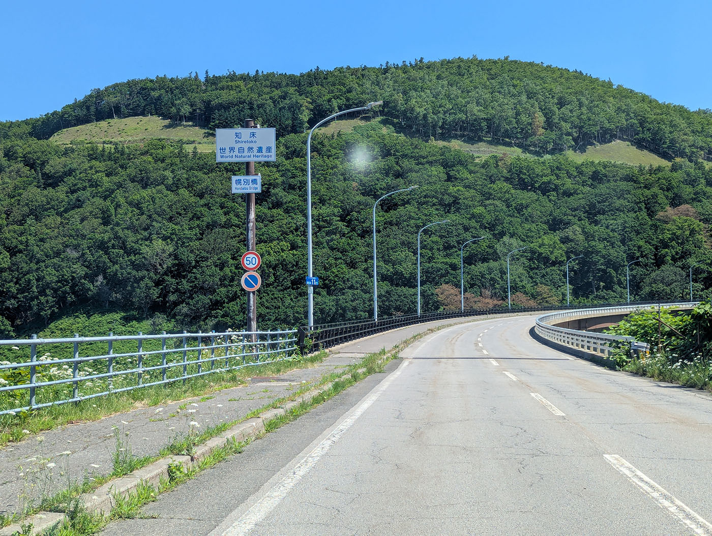 知床峠へ向かう国道334号線。緑豊かな山々と「知床 世界自然遺産」の標識が見える。