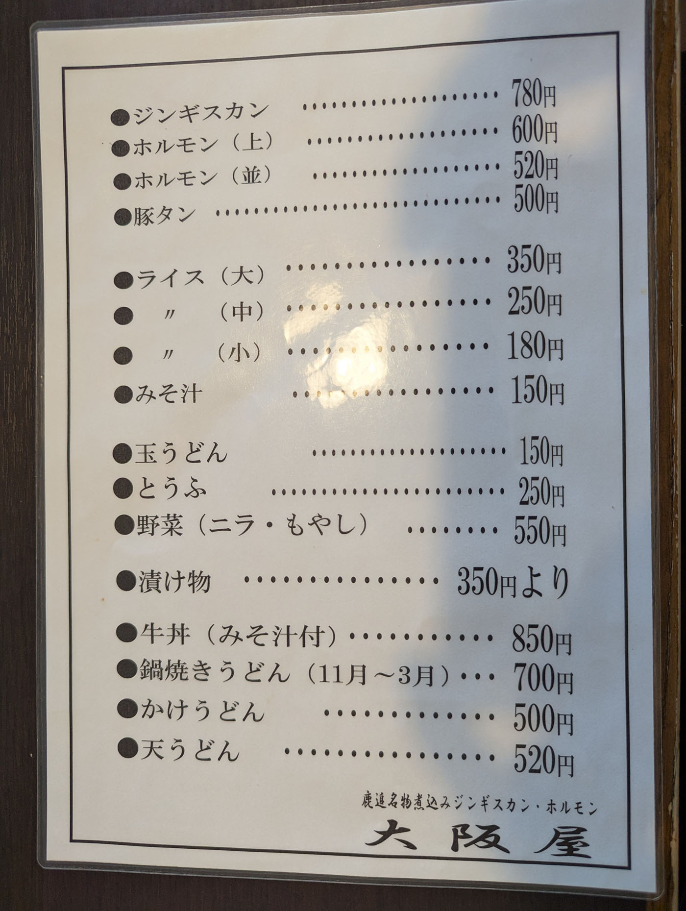 北海道鹿追町「大阪屋」のフードメニュー表。ジンギスカンやホルモン、豚タンに加え、うどんや牛丼などの定食系メニューも掲載されている。
