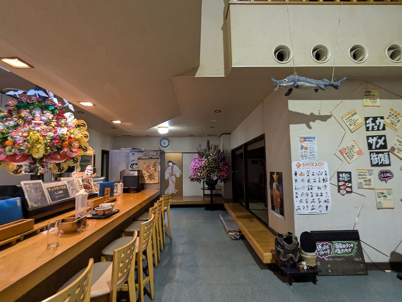 鹿追町のびっくり寿司店内。カウンター席と壁にはチョウザメやキャビア関連の展示、天井から吊るされた魚の飾りも見える。