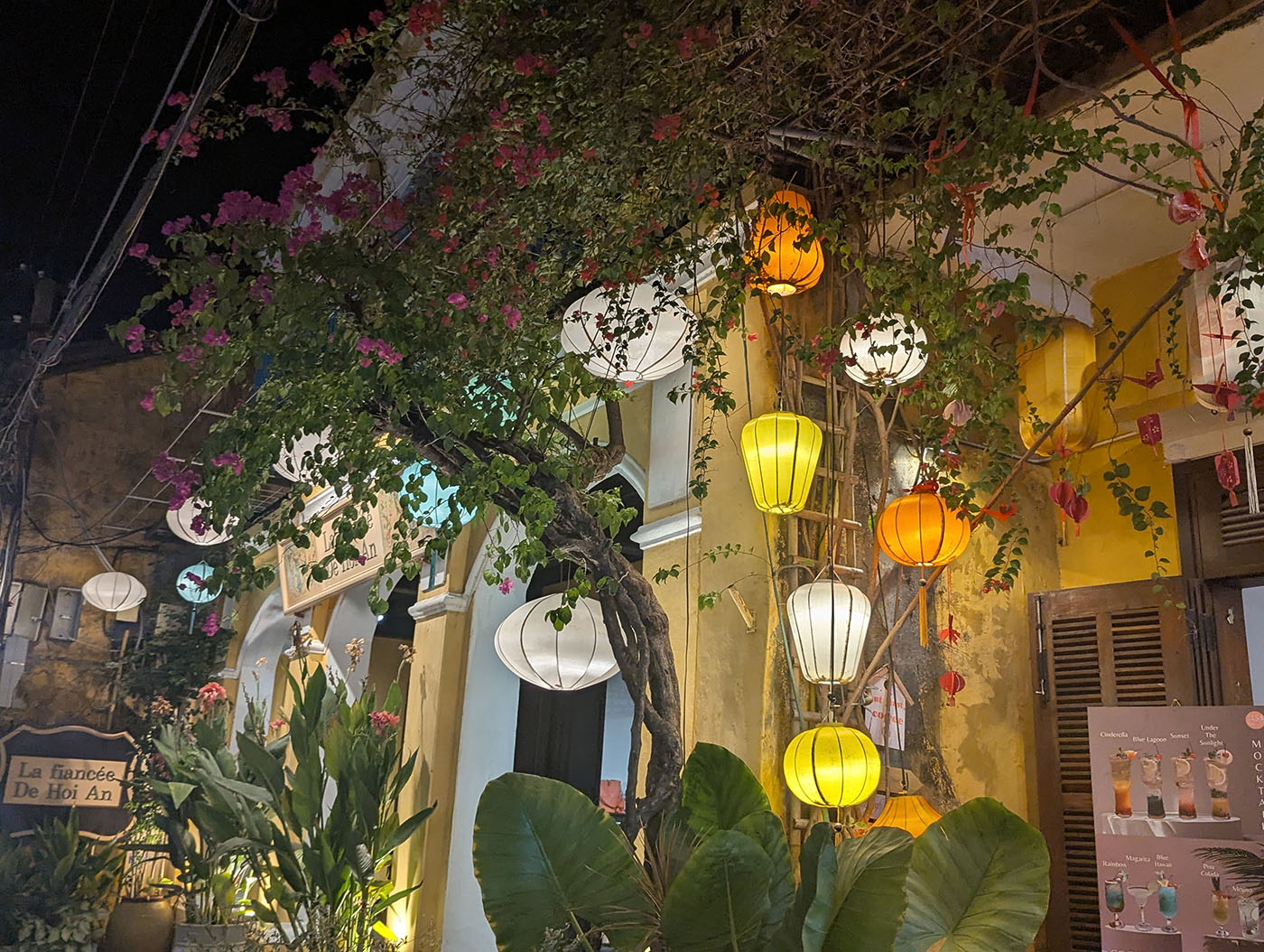 ホイアン旧市街の夜、黄色い壁の建物にブーゲンビリアが絡み、色とりどりのランタンが灯っている様子