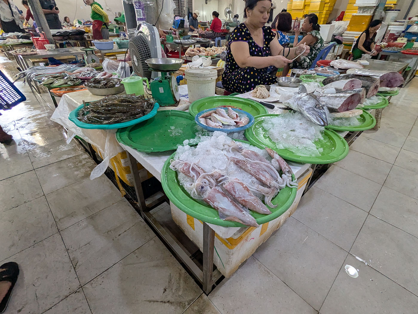 ハン市場の鮮魚コーナーで、氷の上に並べられたイカや魚、エビを売る女性たち