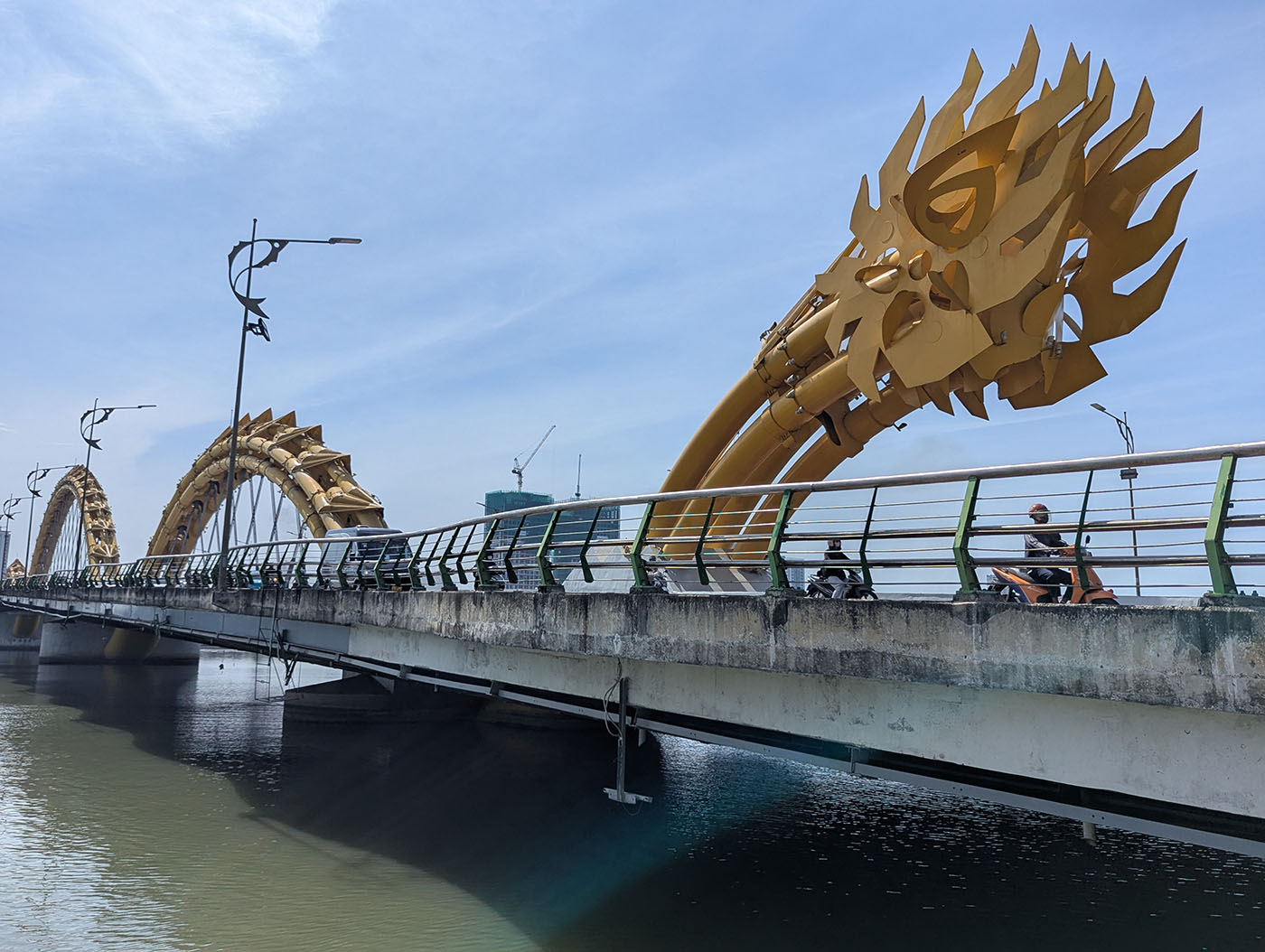 青空の下、金色のドラゴンの頭部が橋の上にそびえるドラゴンブリッジの側面