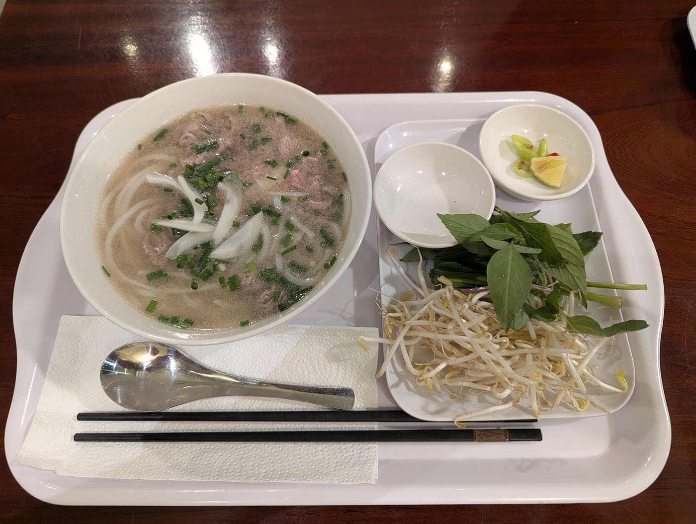 白いトレーに載せられた牛肉フォーと、もやしやハーブ、薬味のセット