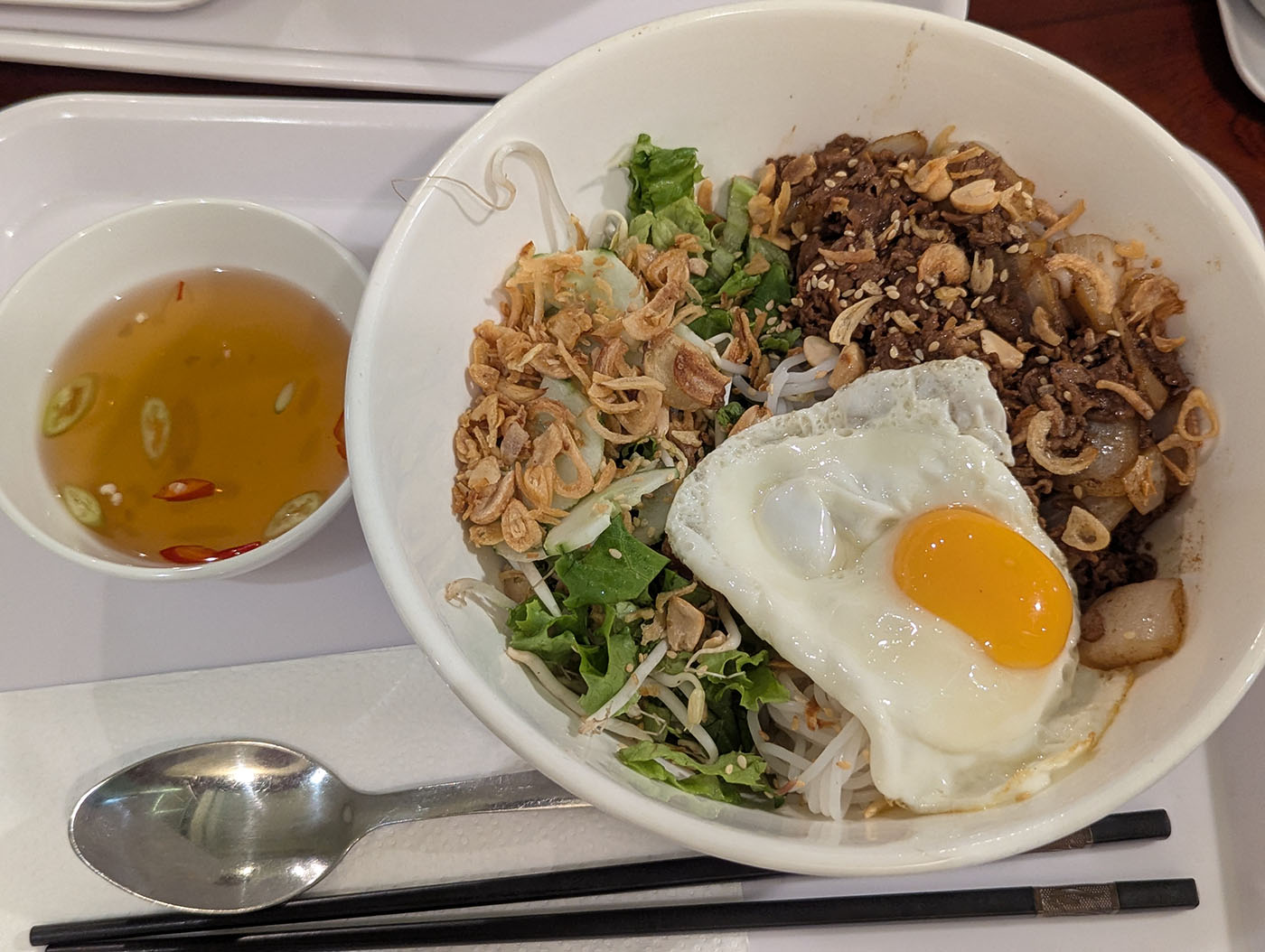 目玉焼きがのった牛そぼろ麺と、横に添えられたヌクチャムの小鉢