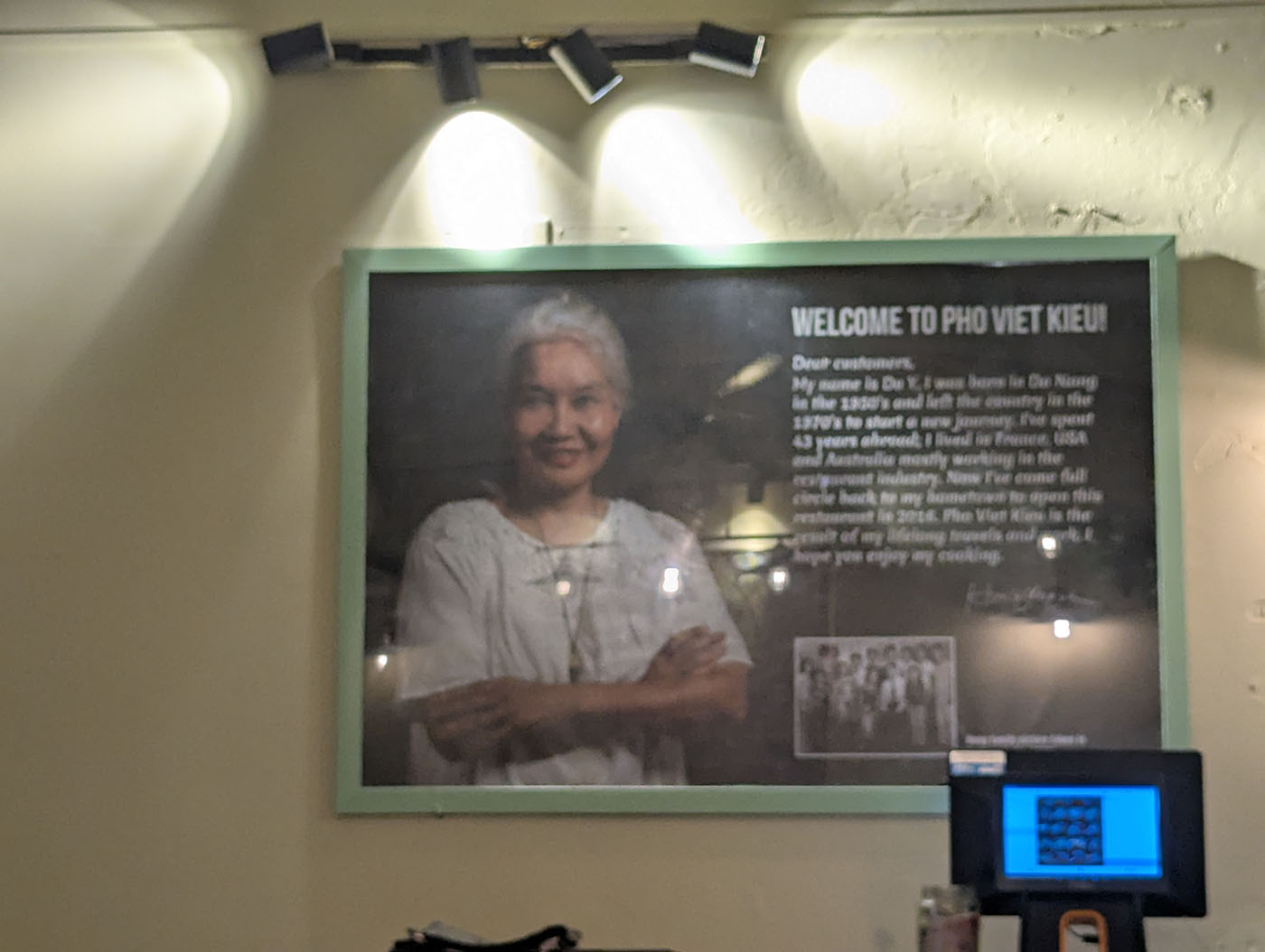 PHO VIET KIEUの店内に飾られた、創業者女性の写真と英語メッセージのボード