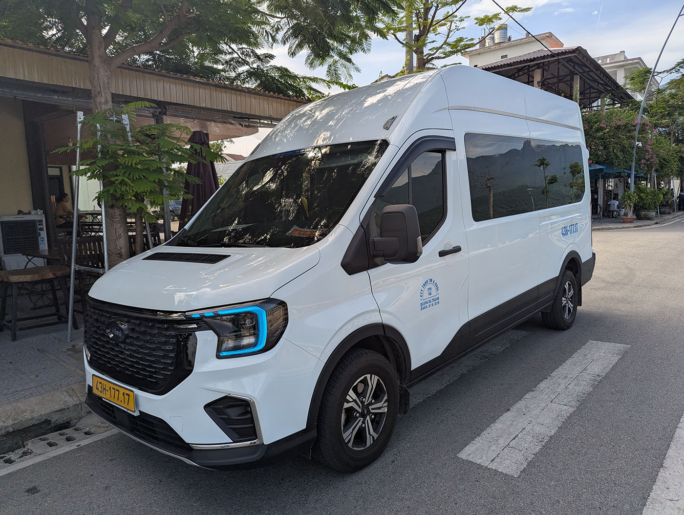 フエへのツアーで利用した白い大型バンが、街路樹のある道端に停車している。