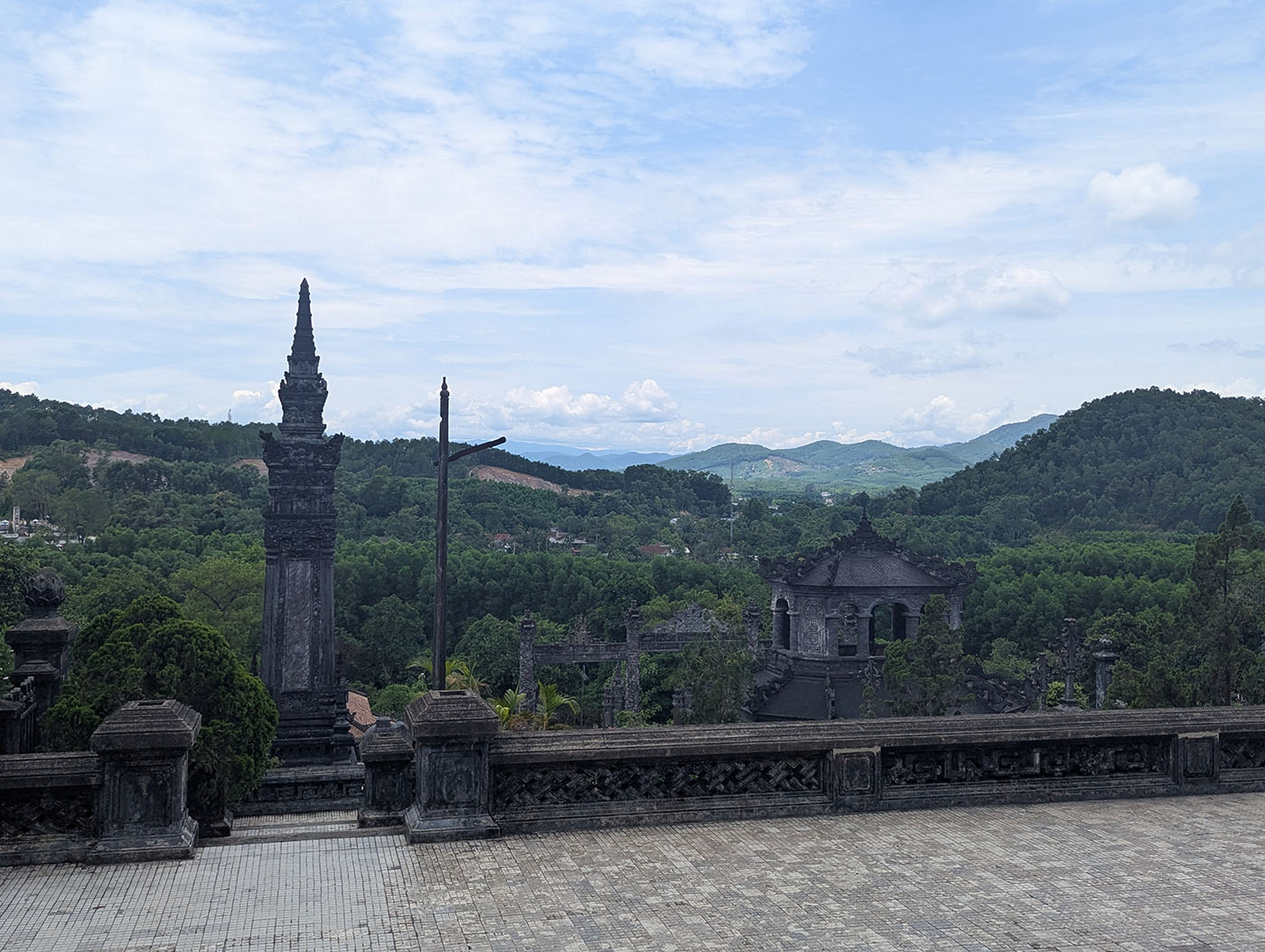 高台から見下ろした寺院全体と周囲の山並み。石造の塔と建築群が緑の中に浮かぶように佇む。