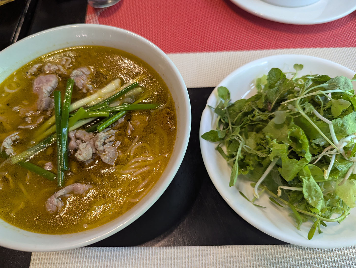 香ばしいスープに細切りの牛肉とネギが浮かぶフォーと、別皿の山盛りハーブ