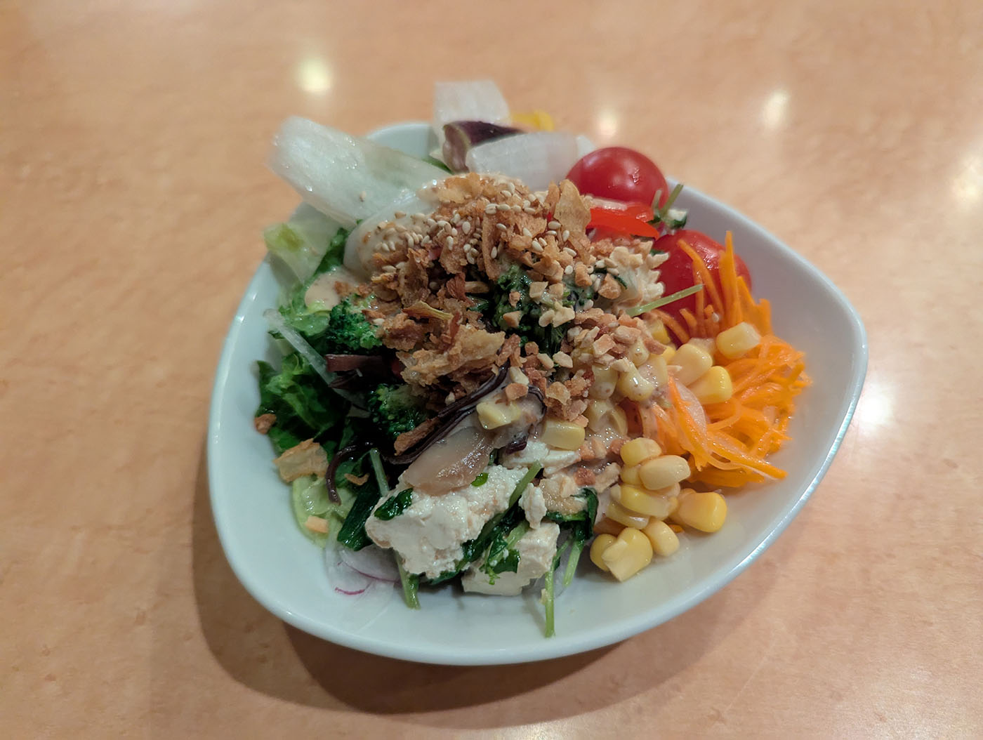 フォルクスのサラダバーで盛りつけた彩り豊かなサラダ。コーンやトマト、豆腐、フライドオニオンがのる。