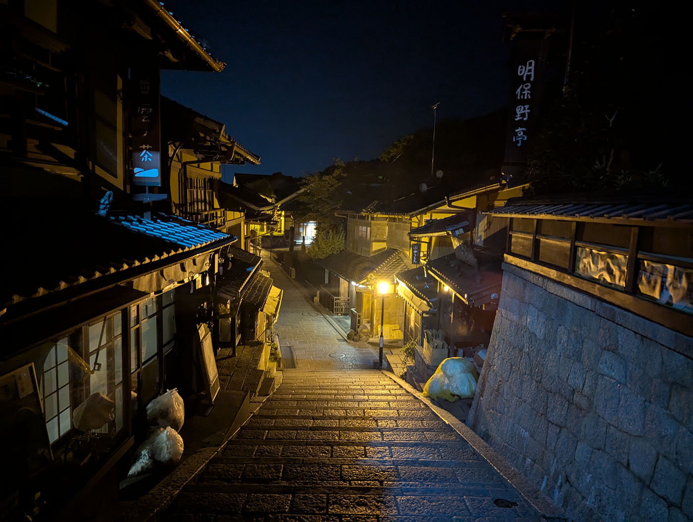 夜の二寧坂を見下ろす。石畳に街灯の光が反射し、静まり返った京都の町並みが続く。