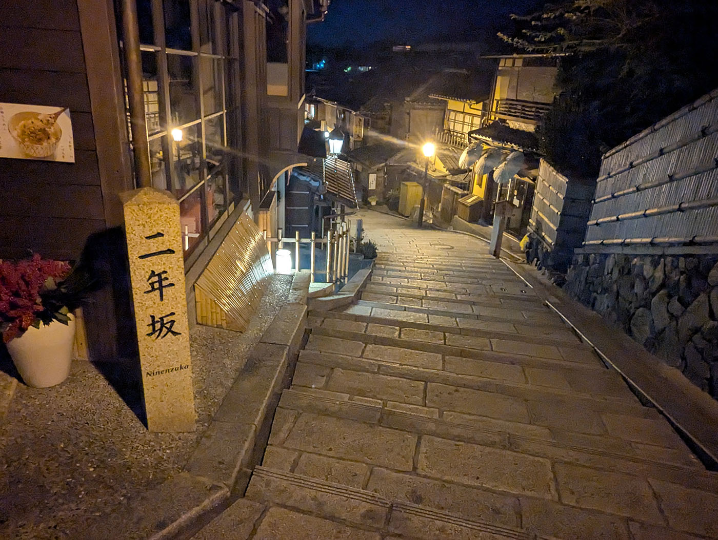 夜の二年坂。石畳の坂道と「二年坂」の碑が街灯の光に照らされる京都の風景。