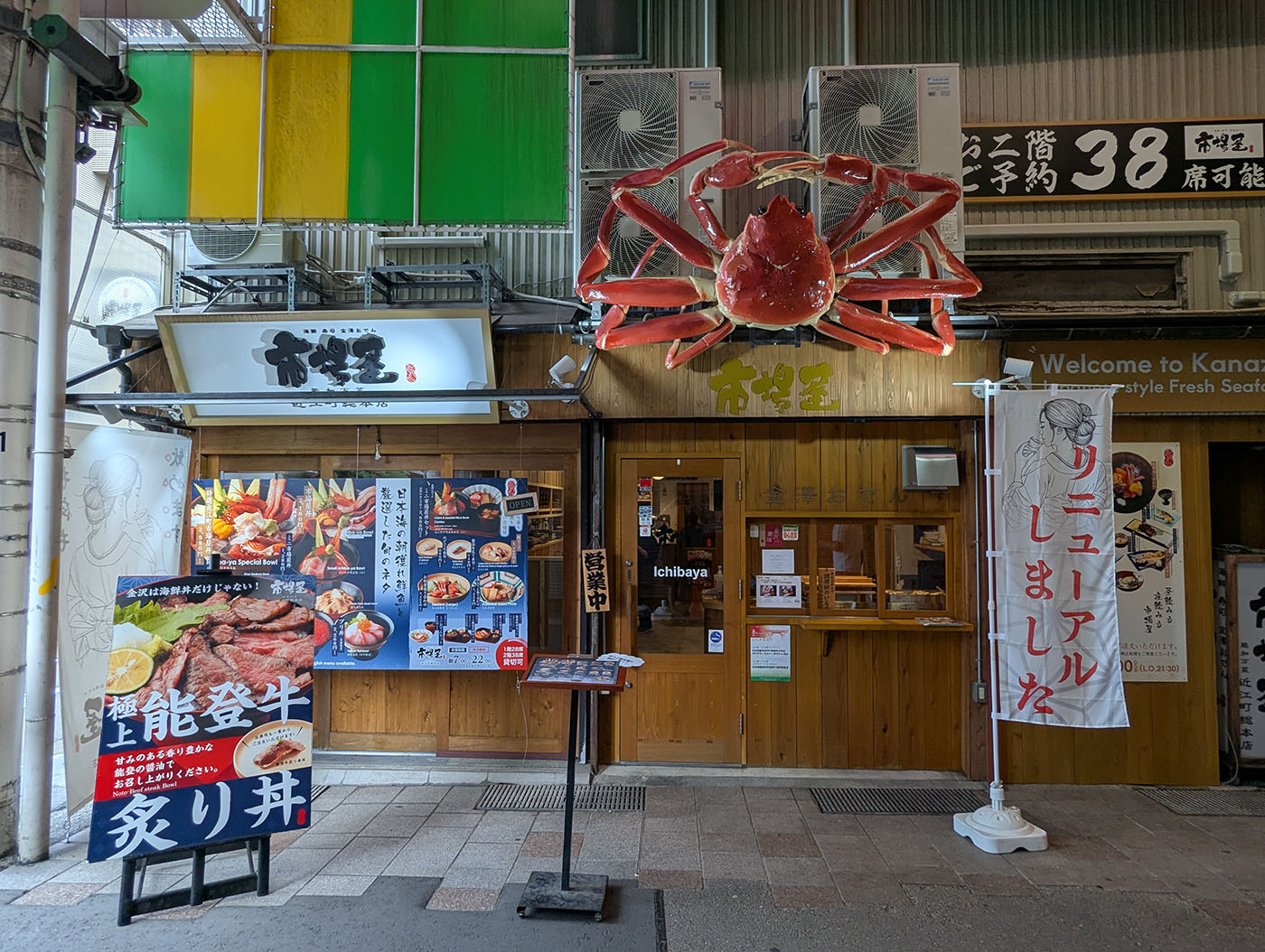 金沢・近江町市場の「市場屋」本店外観。巨大なカニのオブジェと能登牛炙り丼の看板が目を引く海鮮食堂。