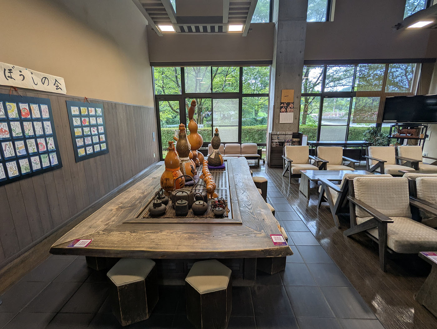 道の駅倶利伽羅塾の館内ラウンジ。木の囲炉裏テーブルを囲み、ひょうたんのオブジェと地元の絵手紙が飾られた温もりある空間。