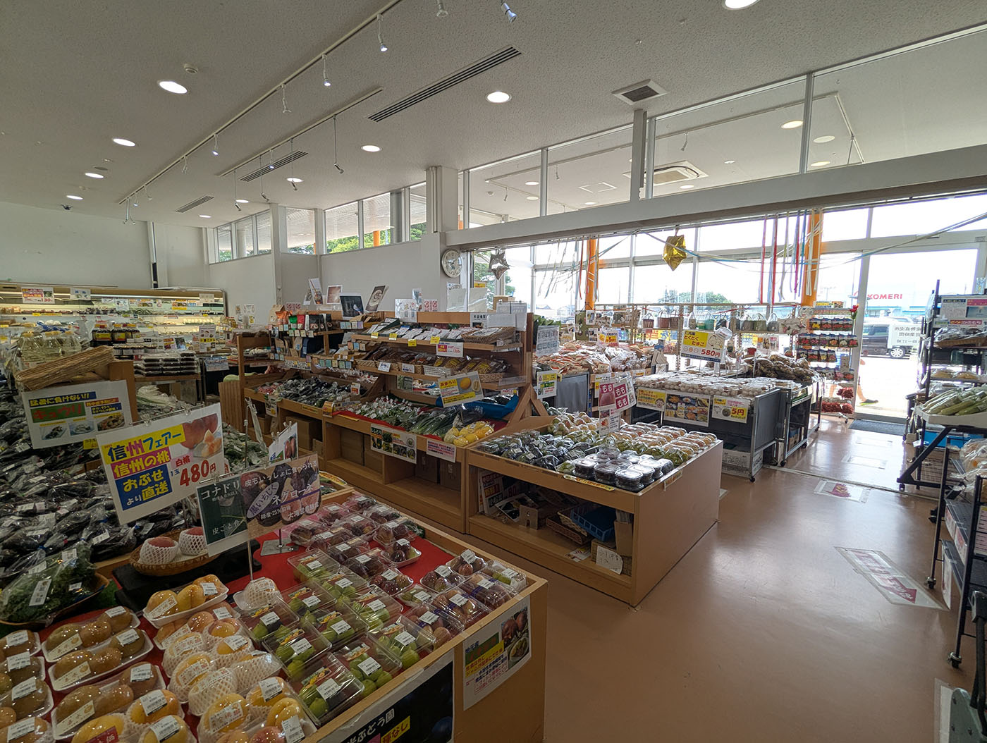 道の駅メルヘンおやべの直売所内部。明るく清潔な店内に、野菜、果物、加工品、土産物が木製の棚や冷蔵ケースに整然と並び、手前には地元産の惣菜や餅が陳列されている。