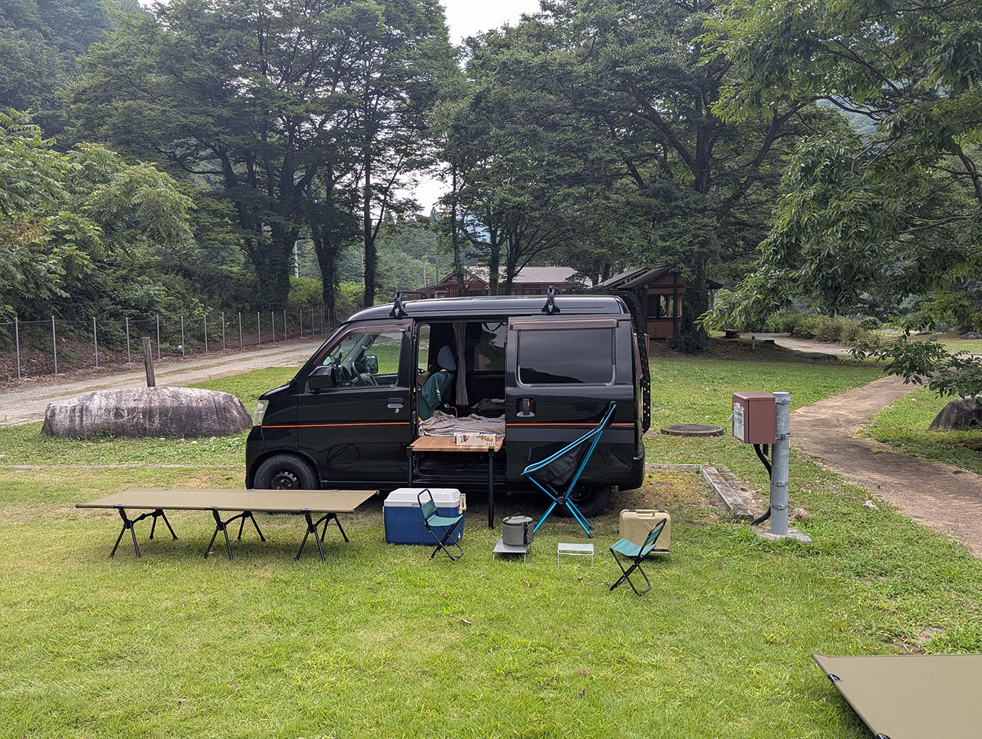 片貝山ノ守キャンプ場で車中泊の準備をする黒いハイゼットカーゴ。テーブルやチェア、コットを並べた静かな森のキャンプサイトの風景。