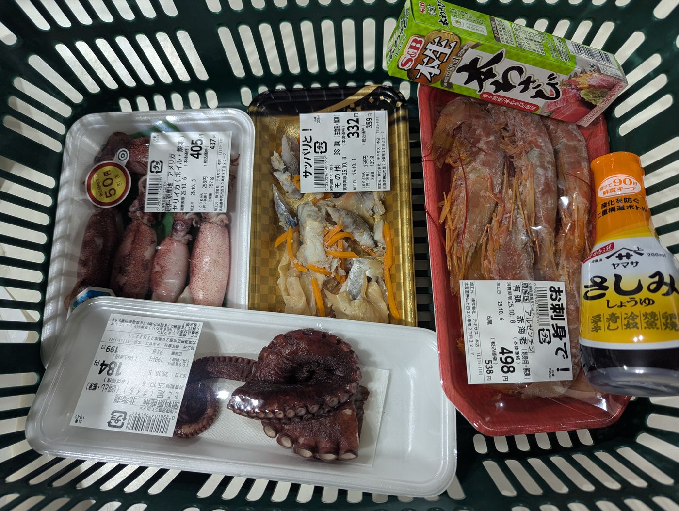 買い物カゴに入れた有頭海老の刺身、ヤリイカ、ボイルたこ、わさびと醤油