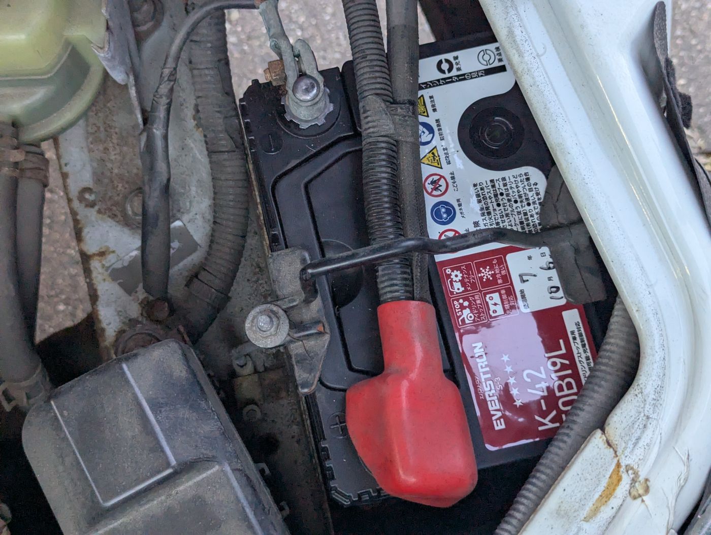 ハイゼットカーゴのエンジンルーム内に装着された新品バッテリーとマイナス端子の位置。