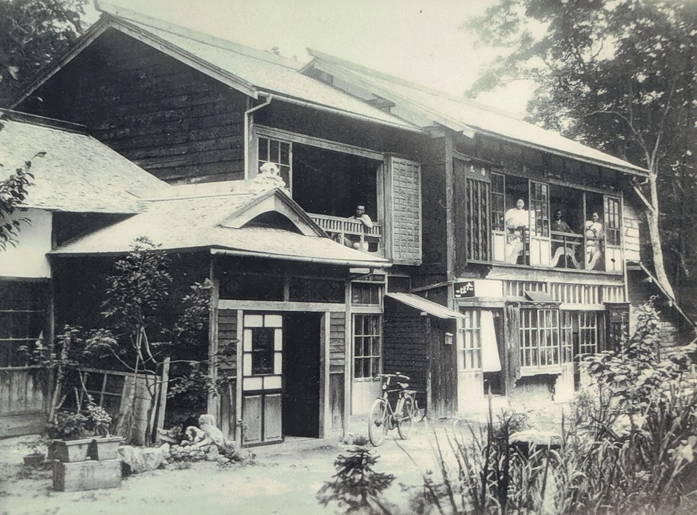 開業当時の湯元館の木造建築と縁側に佇む人々（昭和初期）