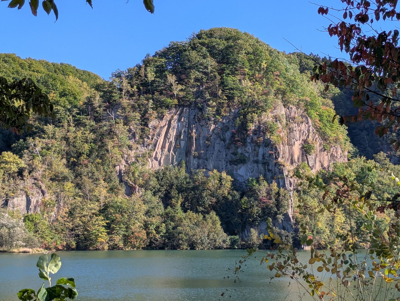 くったり湖畔にそびえるカムイロキの絶壁。神が座る場所とされてきた岩壁が、静かな水面の向こうに立ち上がっている。
