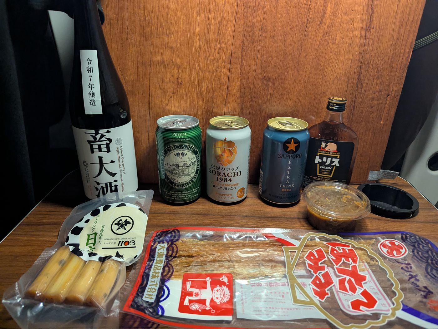 鹿追の道の駅での居酒屋車中泊。畜大酒と北海道のビール、つまみを並べた車内の即席カウンター。