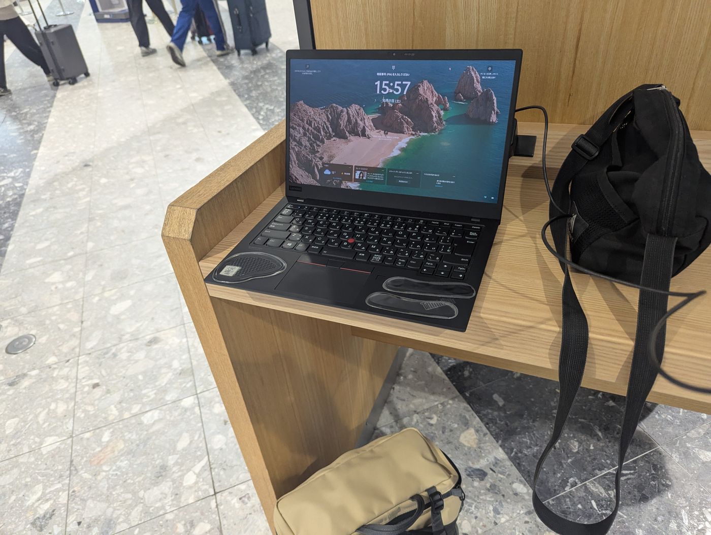 新千歳空港の共有デスクに置かれたノートパソコンとバックパックの作業風景