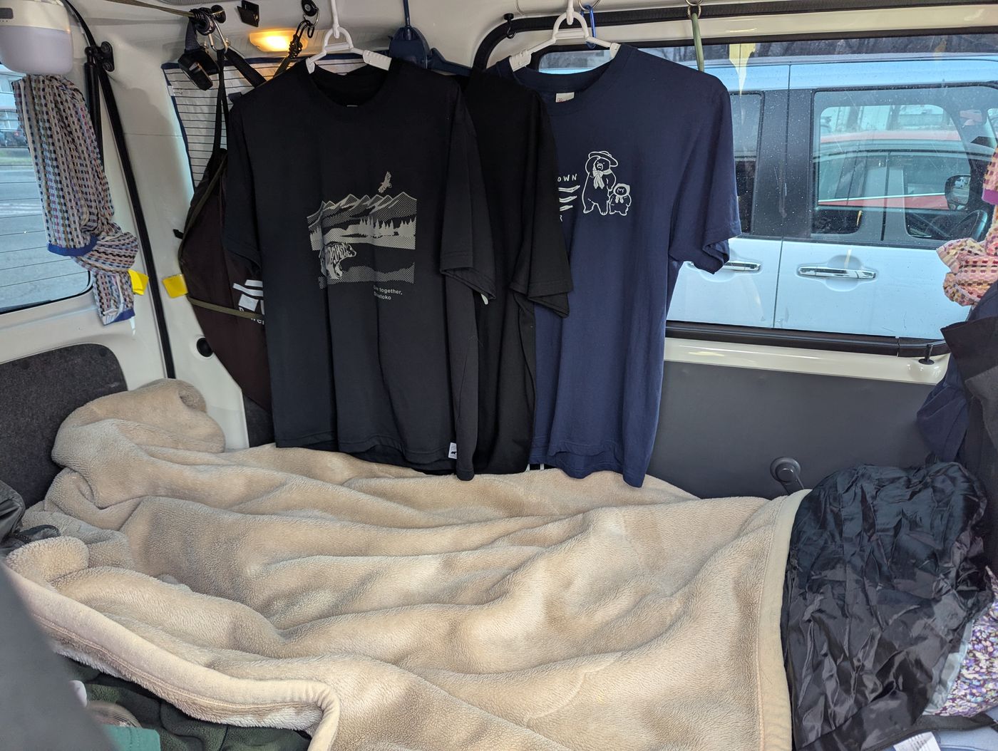 車内に干したTシャツと、結露のない窓。毛布を敷いた車中泊の寝床の様子