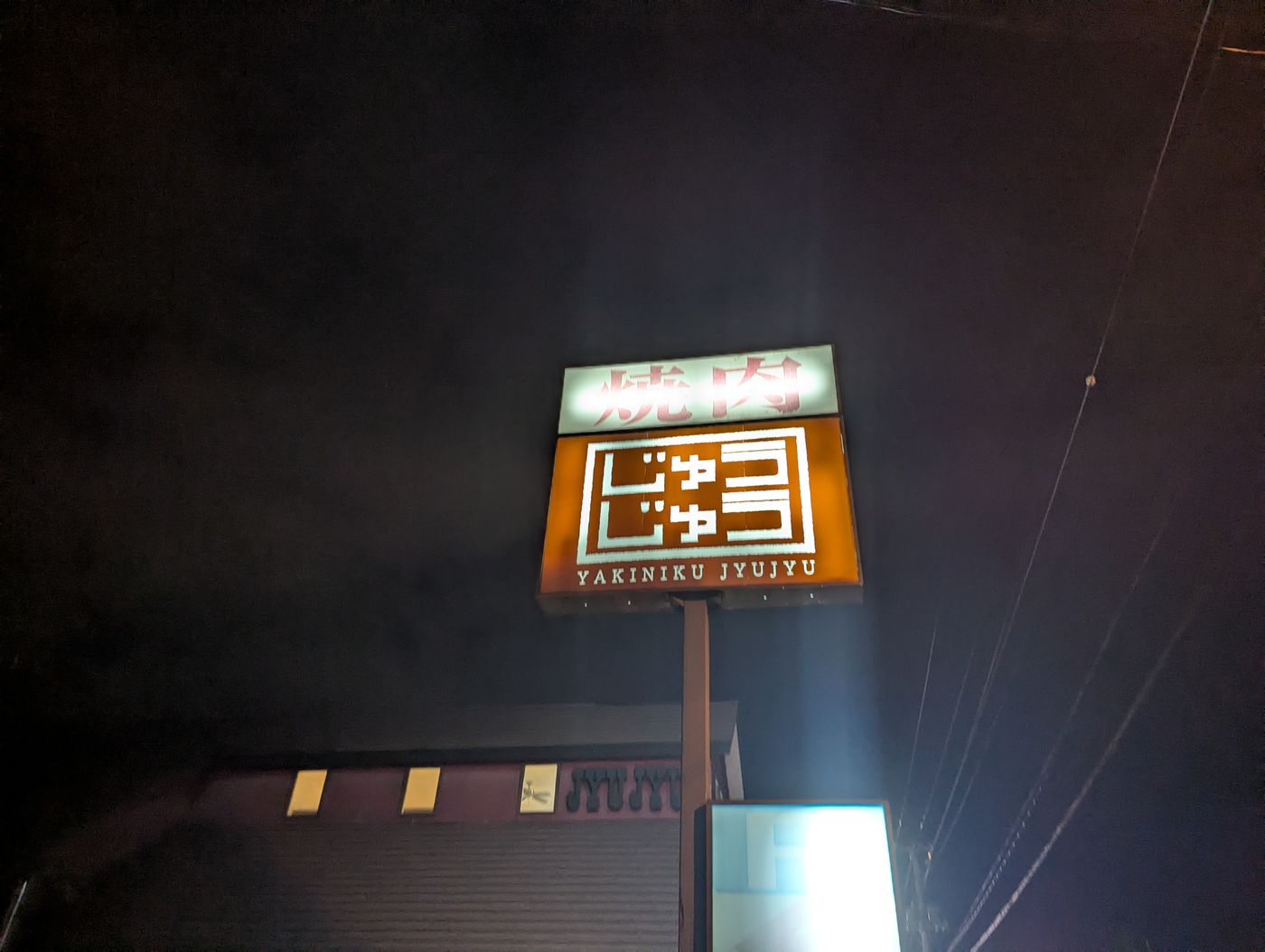 夜の帯広で、焼肉店「じゅうじゅう（YAKINIKU JUJYU）」の看板が暗闇に光っている様子