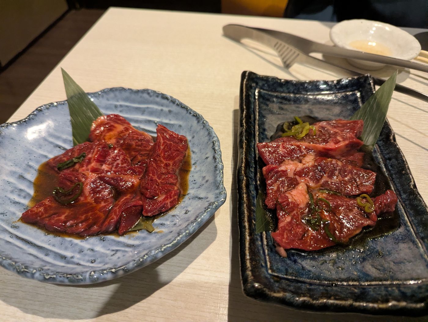 帯広の焼肉店で、タレに漬けた赤身肉が青い皿と黒い皿に盛られてテーブルに並んでいる様子