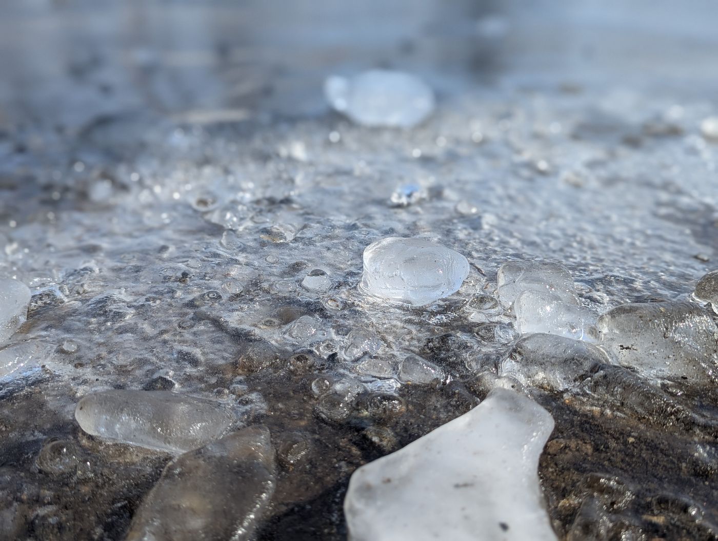 帯広の駐車場の凍った地面に散らばる小さな氷の粒が、ジュエリーアイスのように輝いている風景