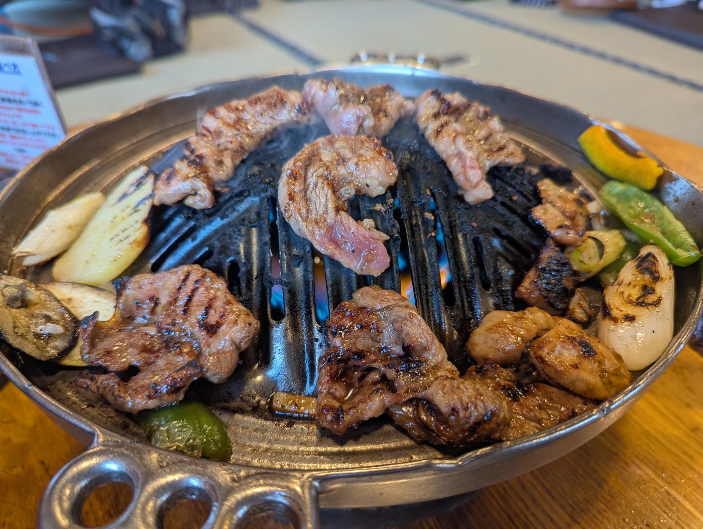 帯広のジンギスカン店で、炭火の上でマトンと野菜を焼いている様子