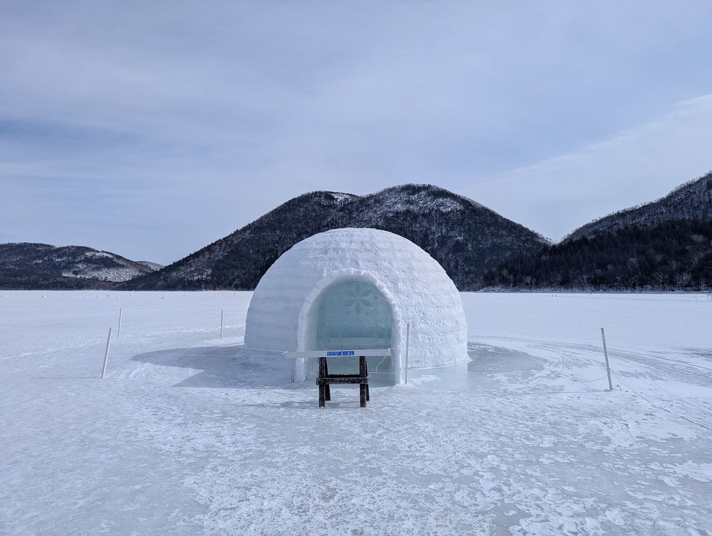 然別湖コタンの氷のイグルーと雪原、背後に連なる雪化粧の山々