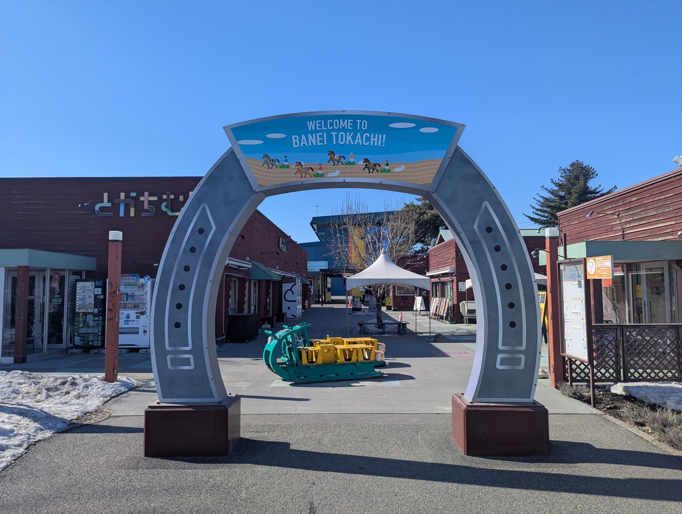 帯広のばんえい競馬場入口にある馬蹄形のゲート「WELCOME TO BANEI TOKACHI」と、とかちむらの建物